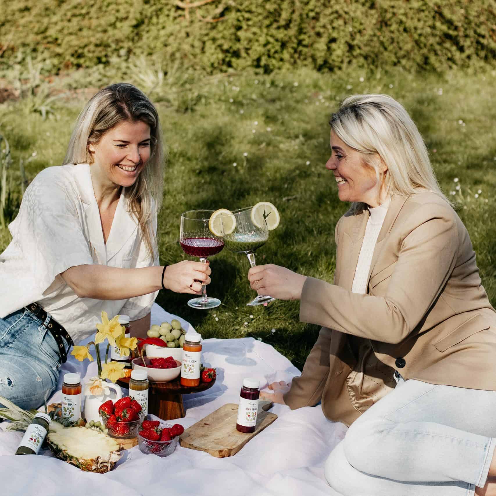 twee vrouwen drinken groentesappen van Zuss & Sap op een picknick in de natuur