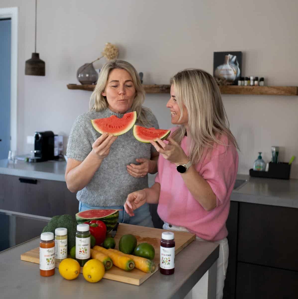 twee blije zussen in de keuken met groentesap van Zuss & Sap